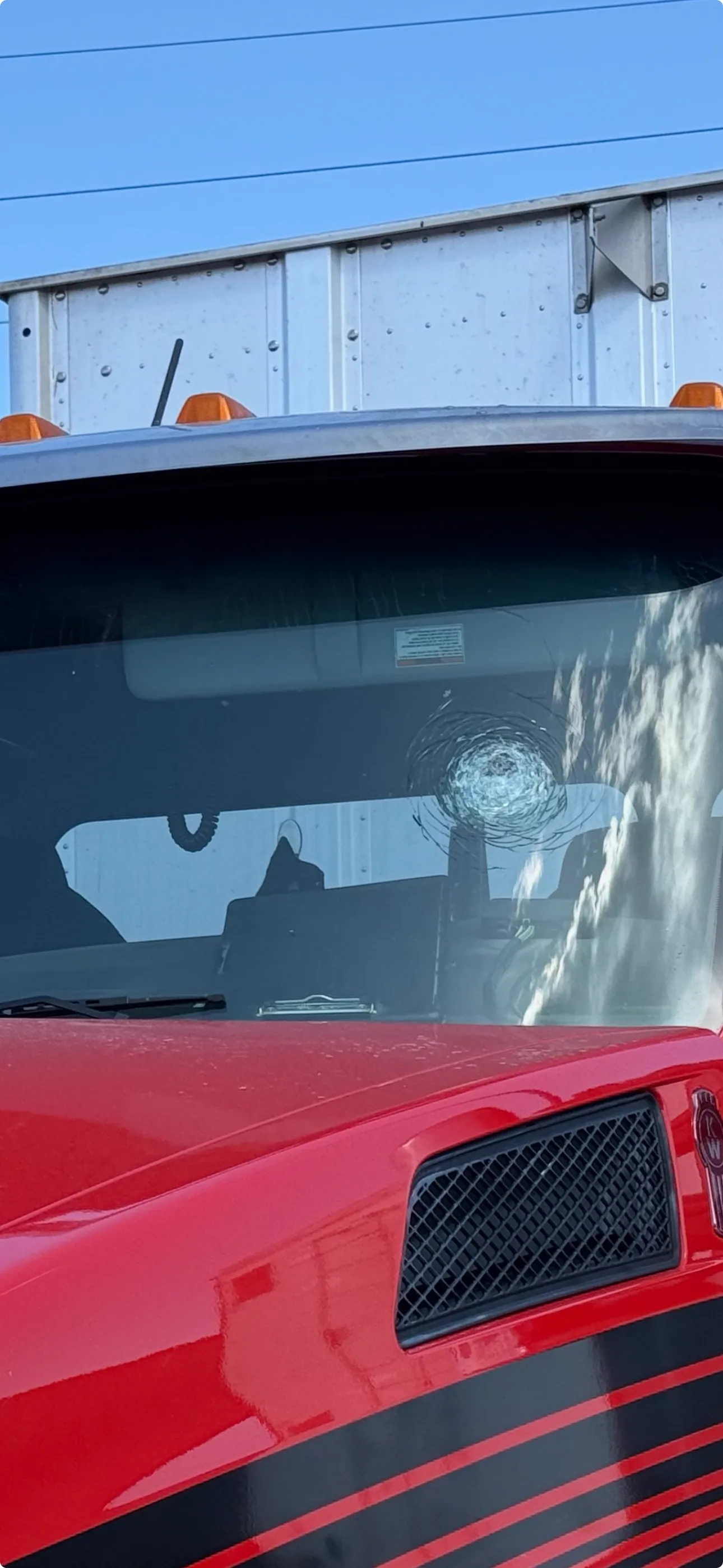 Bullseye rock chip on a red Kenworth semi truck windshield