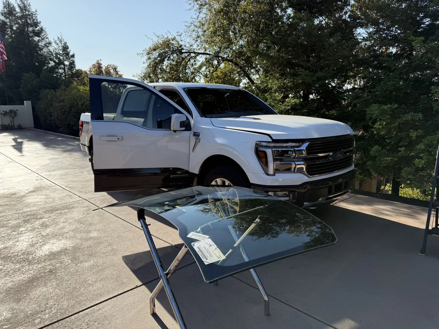 New windshield on stand ready for installation on a white Ford F-150 in Rocklin, CA